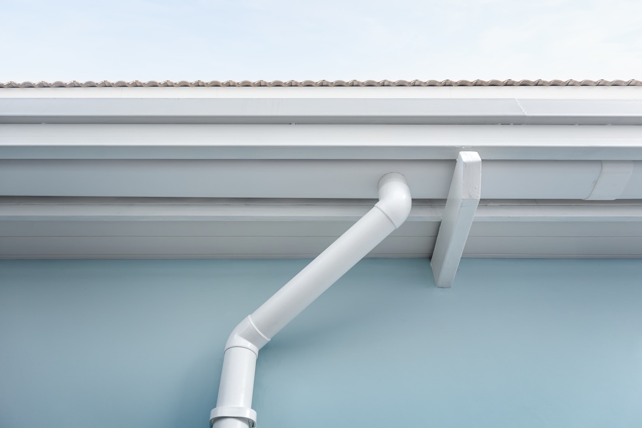 Rain gutter connect to downspout for water drainage system. Rain gutter install on steel structure, connect to pvc downpipe or downspout, elbow at eaves, exterior house building. Also called guttering or eavestrough for water drainage system. Look new clean.