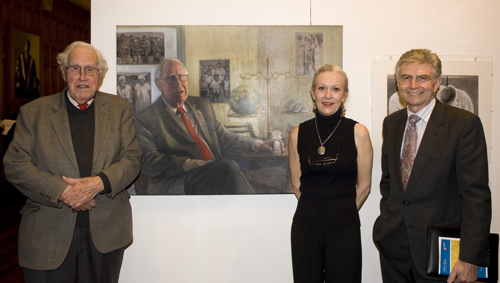 Avril Thomas with Basil Hetzel AC and the Minister for Arts and Health John Hill in front of her oil portrait painting of Basil Hetzel at Adelaide University exhibition in Boynton Hall