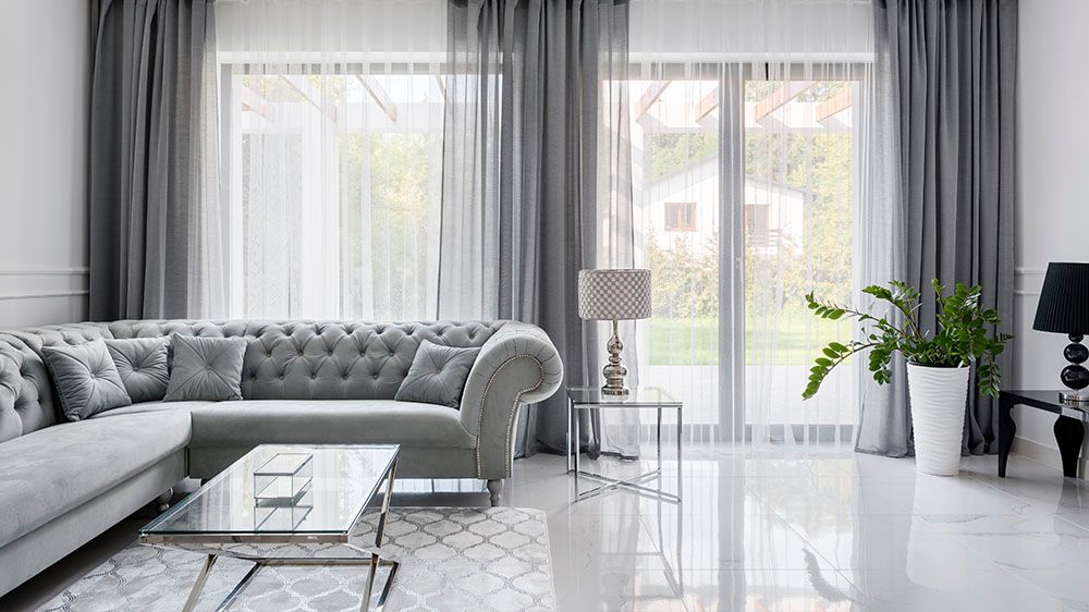 Modern living room with white sheer curtains showcasing natural light and elegant window coverings.