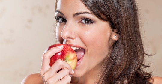 Pretty young woman eating an apple