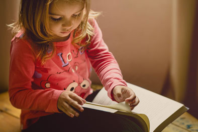 little girl wearing pink reading a book