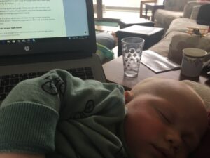 A working parent with a baby in their arms