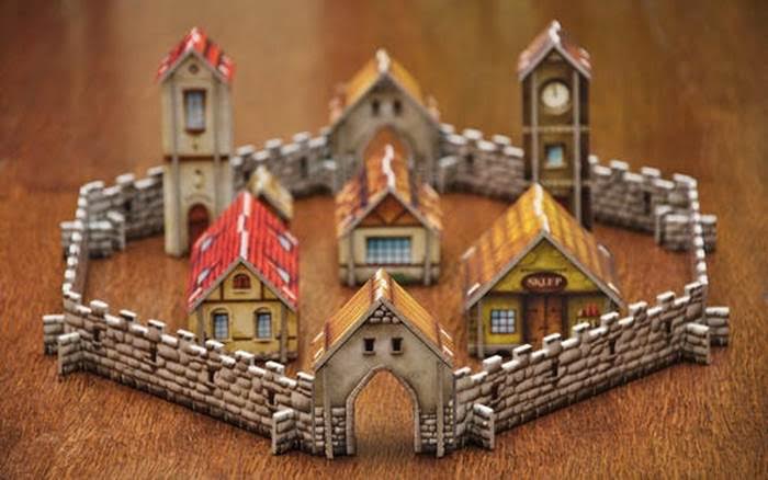 Miniature medieval-style village with stone walls and colorful rooftops, displayed on a wooden surface