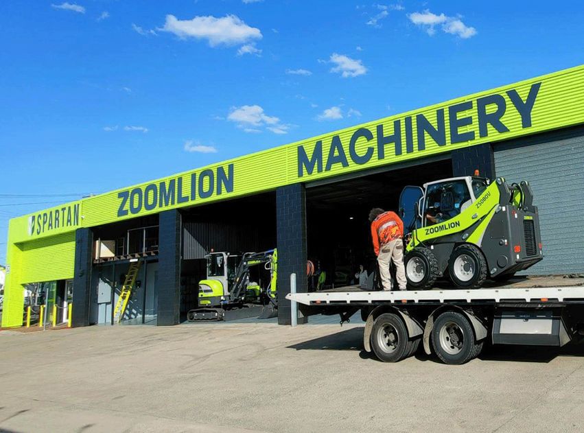 Zoomlion machinery being loaded onto a transport truck at a dealership | Spartan Machinery
