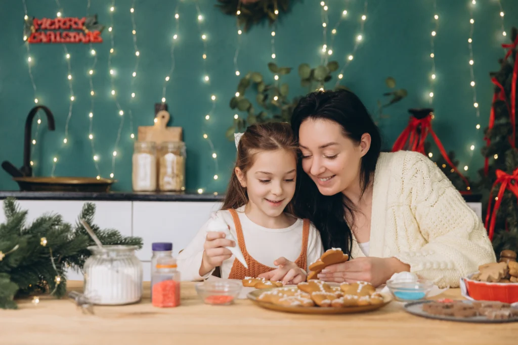 mother and daughter baking gingerbread cookies in kitchen with christmas lights and decorations | Swoosh Finance