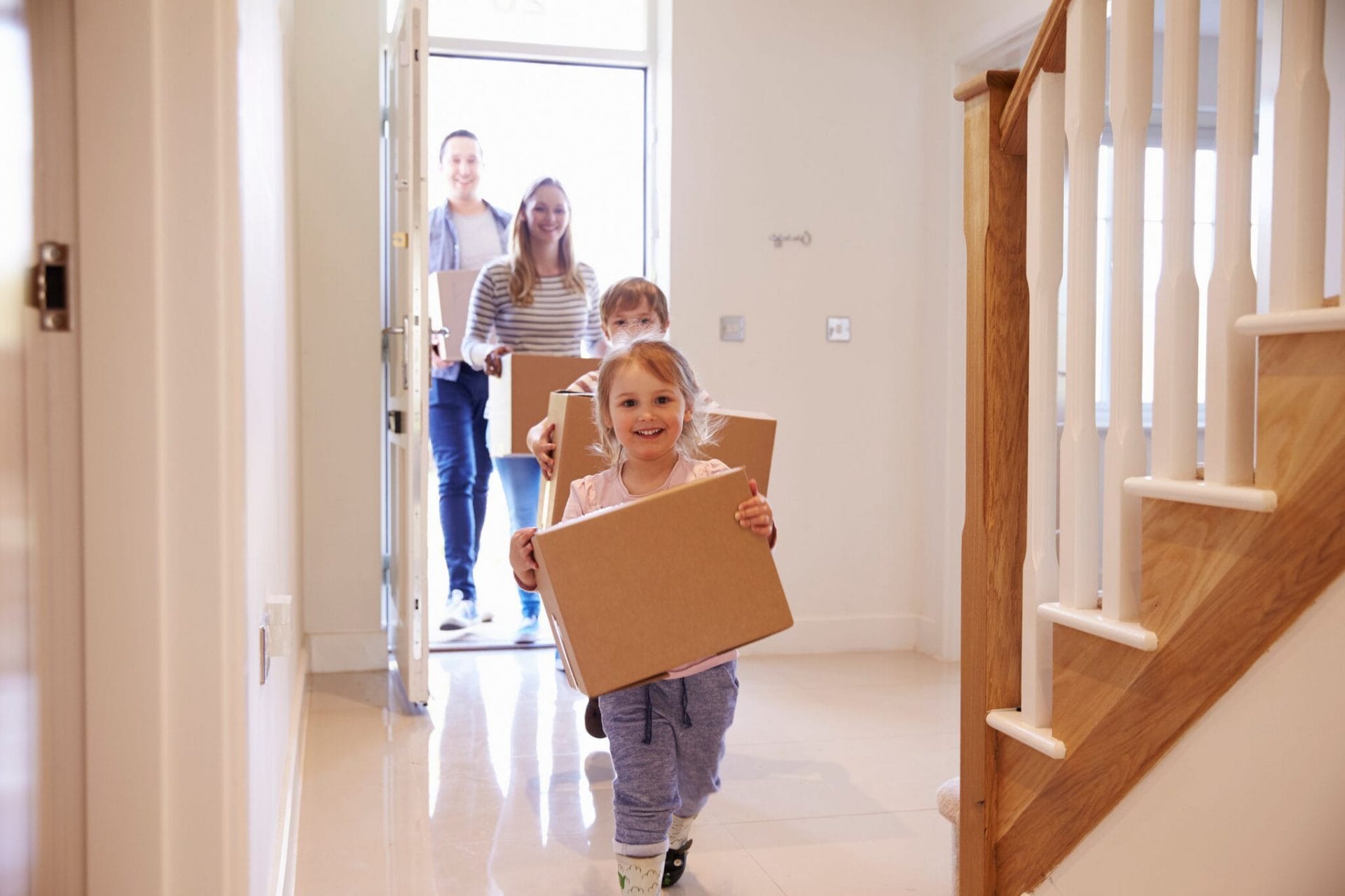family carrying boxes into home