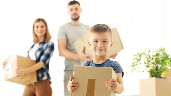 a young family carrying cardboard boxes while moving house