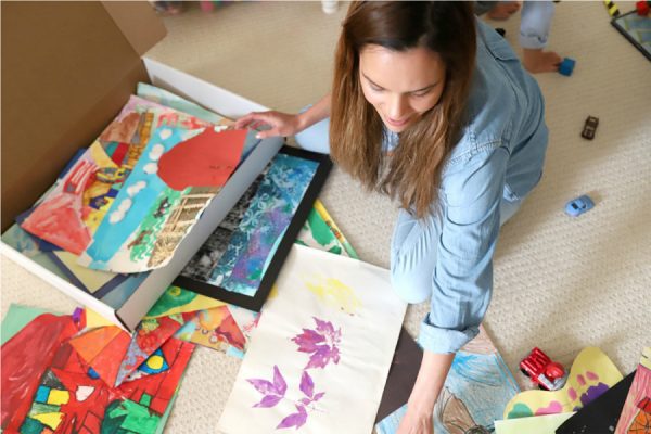 a mother storing her kids artwork in a flat cardboard box