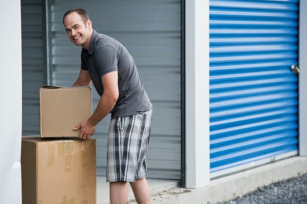 a man putting cardboard boxes in a storage unit