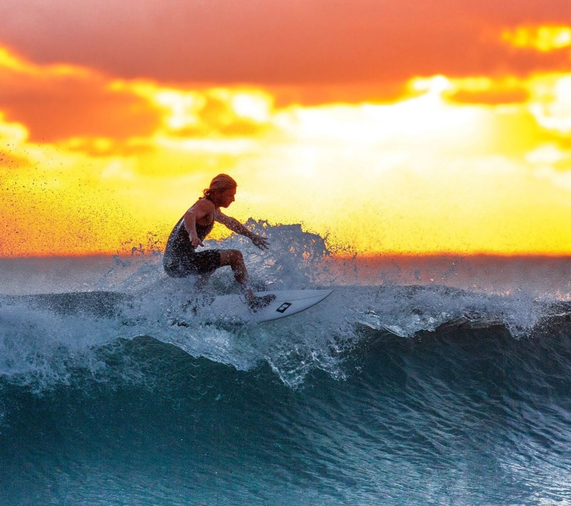 Personal performance man surfing over water with a sunrise background