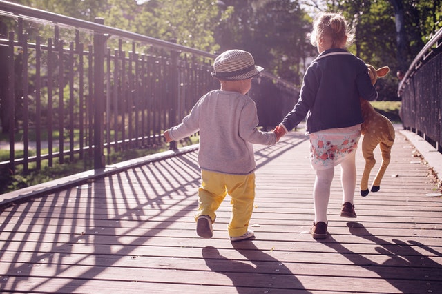 Young boy and young girl holding hands while walking on a bridge
